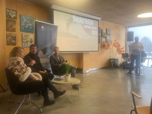 Remigrācijas uzņēmēju forums Ungurpilī – diskusija ar runātājiem, fonā prezentācijas ekrāns un Vidzemes plānošanas reģiona simbolika.