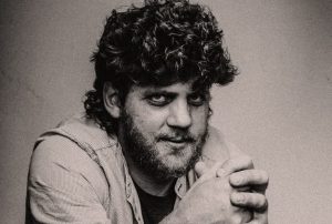 Melnbalts portrets: vīrietis ar kupliem, cirtainiem matiem