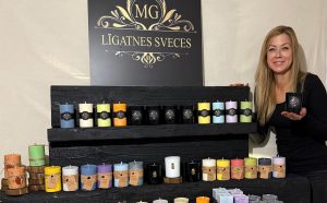 Jaunā sieviete stāv pie stenda ar svecēm